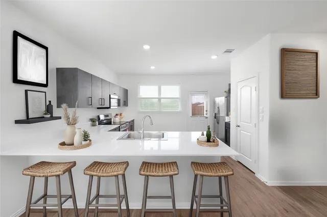 a kitchen with stainless steel appliances kitchen island granite countertop a dining table chairs and a refrigerator
