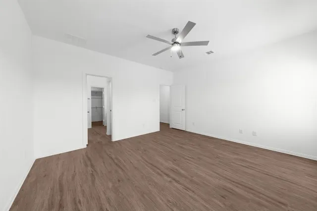 an empty room with wooden floor closet and windows