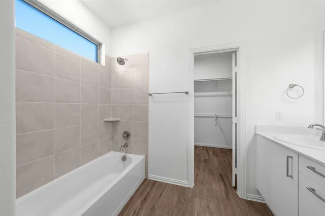 a bathroom with a tub shower vanity and a sink