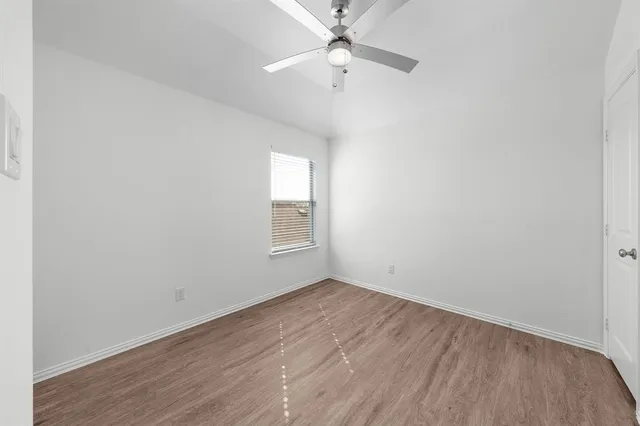 an empty room with a window and a ceiling fan