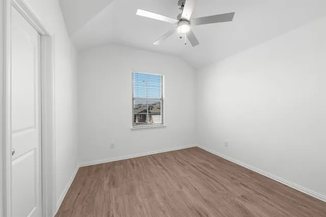 an empty room with a window and ceiling fan