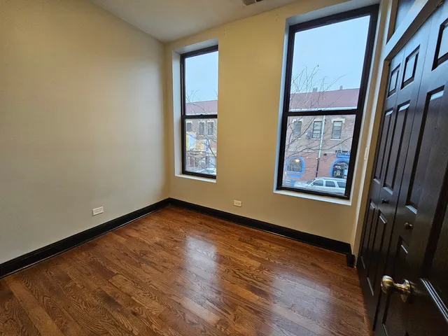 a view of an empty room with glass door and wooden floor