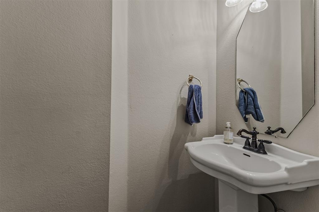 9301 Nottingham Court Rowlett, TX 75088 - Photo 27 of 39 Pedestal sink with a decorative faucet, hexagonal mirror, and wall-mounted lighting
