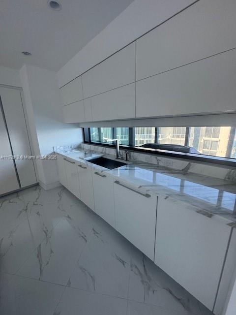 18555 Collins Avenue, Unit 2905 Sunny Isles Beach, FL 33160 - Photo 19 of 40 a kitchen with granite countertop a sink and white cabinets