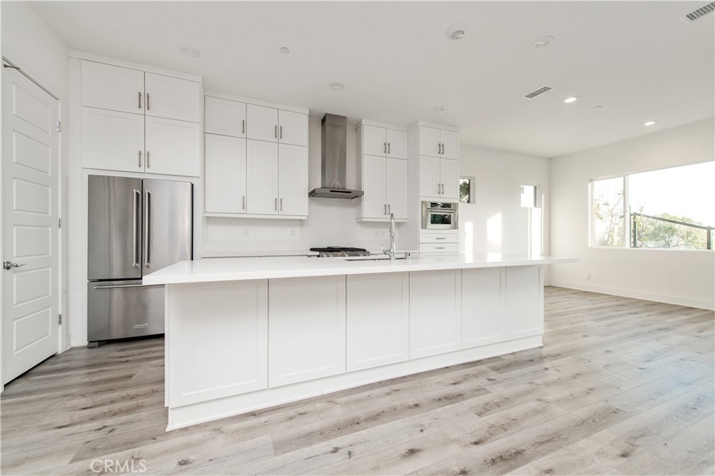 26380 Paseo Sillin San Juan Capistrano, CA 92675 - Photo 12 of 49 a large kitchen with stainless steel appliances a large counter top a wooden floor and cabinets