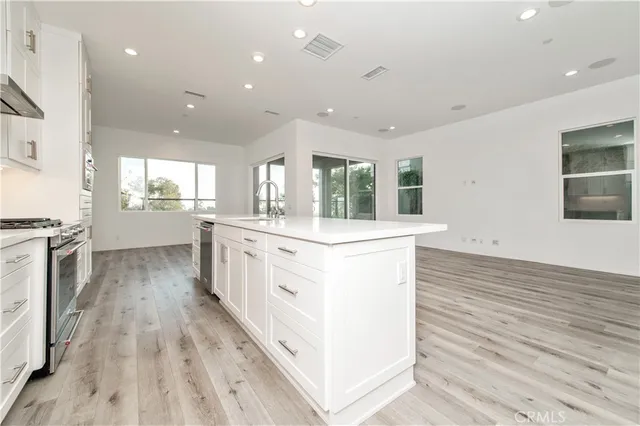 a large kitchen with stainless steel appliances kitchen island a large counter top a sink a stove and a refrigerator