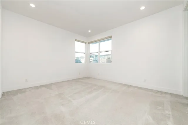 an empty room with white cabinet and windows