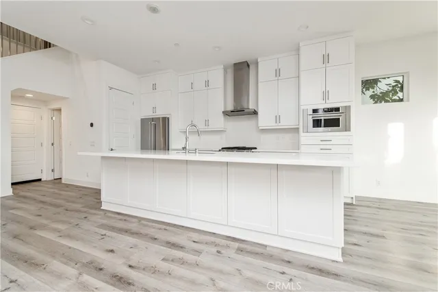 a kitchen with stainless steel appliances cabinets and a wooden floor