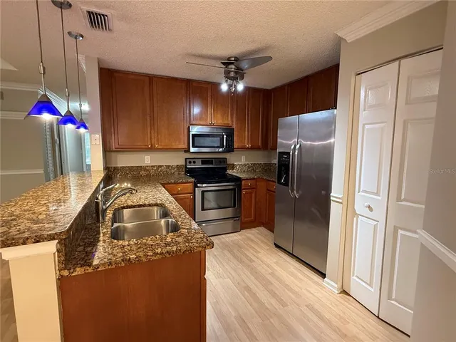 a kitchen with granite countertop stainless steel appliances a stove refrigerator and microwave