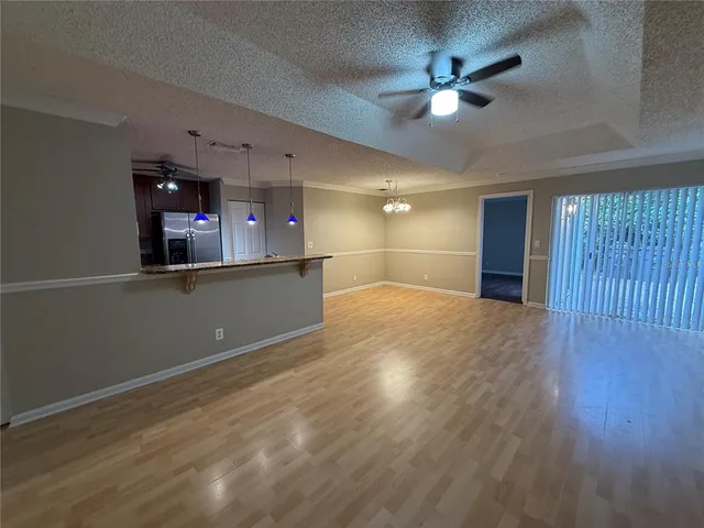 a view of a livingroom with a ceiling fan wooden floor and a ceiling fan