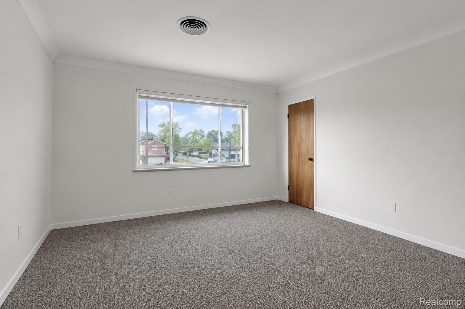 5223 Allen Road Allen Park, MI 48101 - Photo 9 of 12 Bright room featuring a large window, neutral gray carpet, white walls, and a natural wood-finish door