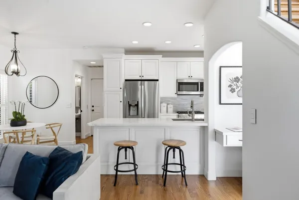a living room with stainless steel appliances furniture a dining table and kitchen view