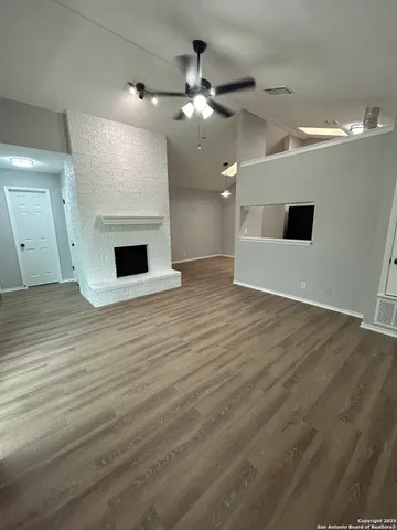 an empty room with wooden floor fireplace and windows