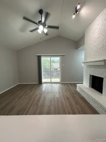 a view of an empty room with wooden floor and a fireplace