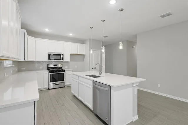 a kitchen with kitchen island a sink a counter top space stainless steel appliances and cabinets