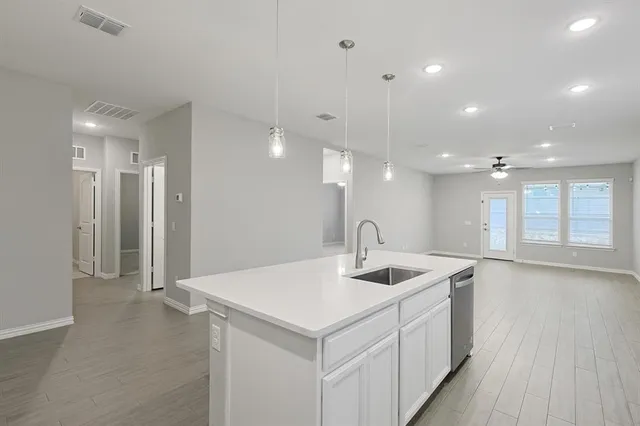 a kitchen with stainless steel appliances a sink cabinets and wooden floor