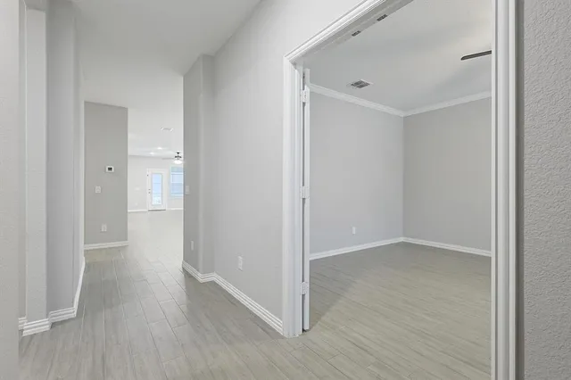 a view of an empty room with a window and wooden floor