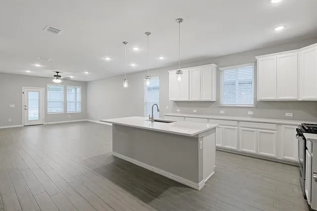 a kitchen with stainless steel appliances sink stove refrigerator and white cabinets with wooden floor