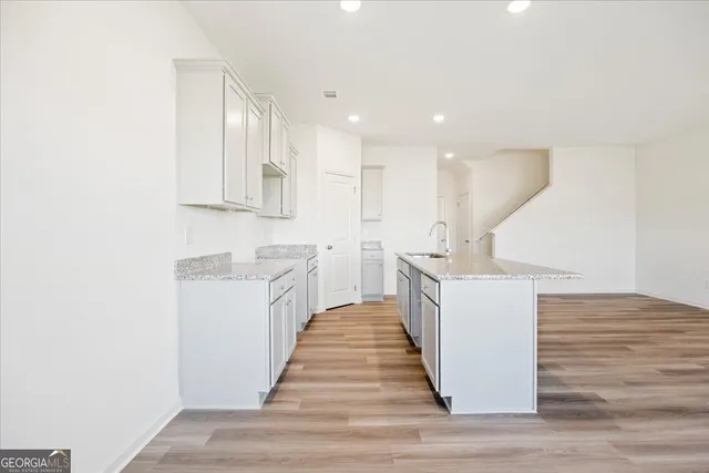 a kitchen with kitchen island sink and white cabinets