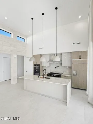 a kitchen with kitchen island granite countertop a stove a oven a sink and a cabinets