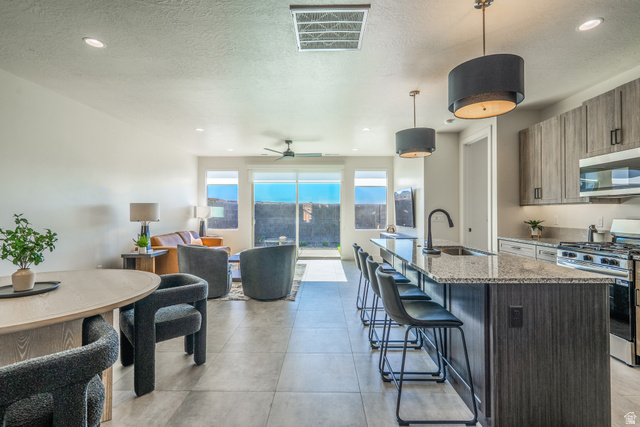 2972 West 570 North Hurricane, UT 84737 - Photo 21 of 104 Kitchen with stainless steel appliances, a kitchen bar, light stone counters, an island with sink, and ceiling fan