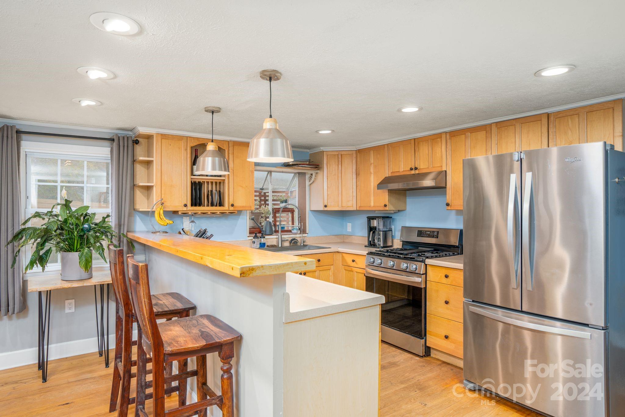 307 Tabernacle Road Black Mountain, NC 28711 - Photo 7 of 27 a kitchen with granite countertop a refrigerator a stove a sink a dining table and chairs with wooden floor