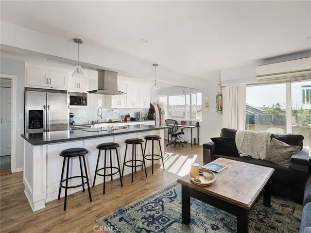 a living room with stainless steel appliances granite countertop furniture a rug kitchen view and a large window