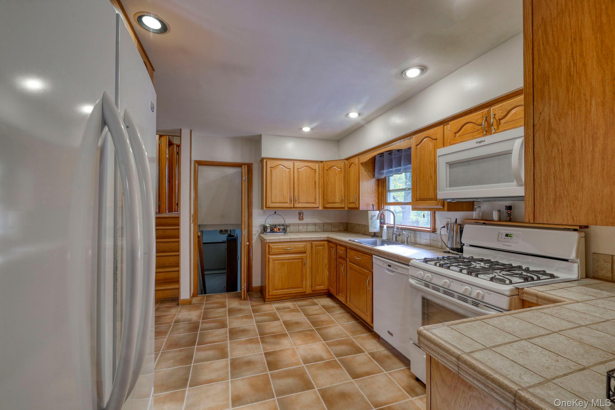 4 Irene Court Fishkill, NY 12524 - Photo 6 of 46 Kitchen with white appliances, tile countertops, recessed lighting, light tile patterned flooring, and light brown cabinets