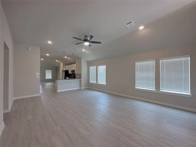 a view of an empty room with a kitchen and a window