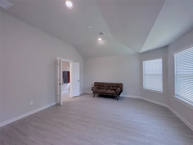 a view of empty room with wooden floor and windows