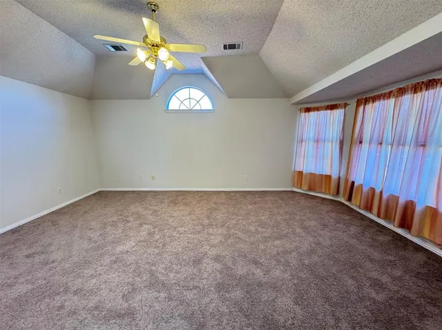 an empty room with a chandelier fan and windows