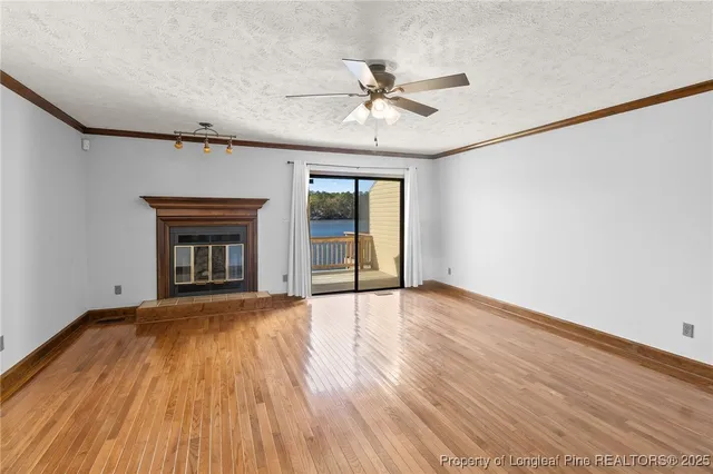 an empty room with wooden floor fireplace and windows