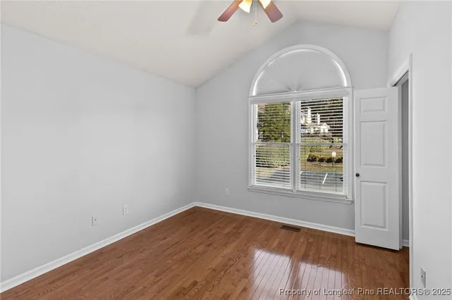 an empty room with wooden floor exposed radiator and windows