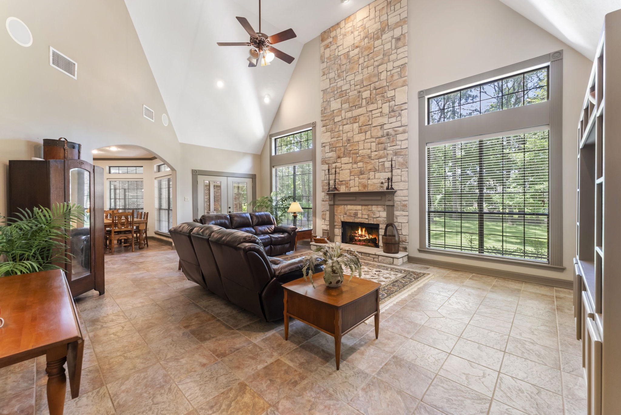 24311 Standing Oak Drive Spring, TX 77389 - Photo 13 of 42 A dramatic stone fireplace rises to the ceiling, framed by tall windows that bring the outdoors in. The open layout keeps everyone connected, whether you’re hosting game night or enjoying a relaxed evening by the fire.
