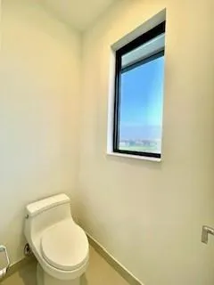 a white toilet sitting next to a white wall
