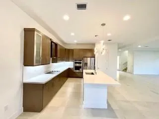 a large white kitchen with kitchen island a sink a counter space and a living room