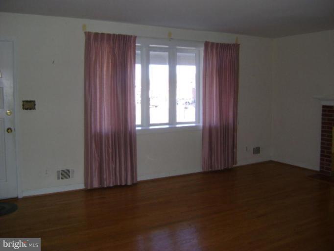 9823 Forge Park Road Perry Hall, MD 21128 - Photo 9 of 14 an empty room with wooden floor and windows with curtains