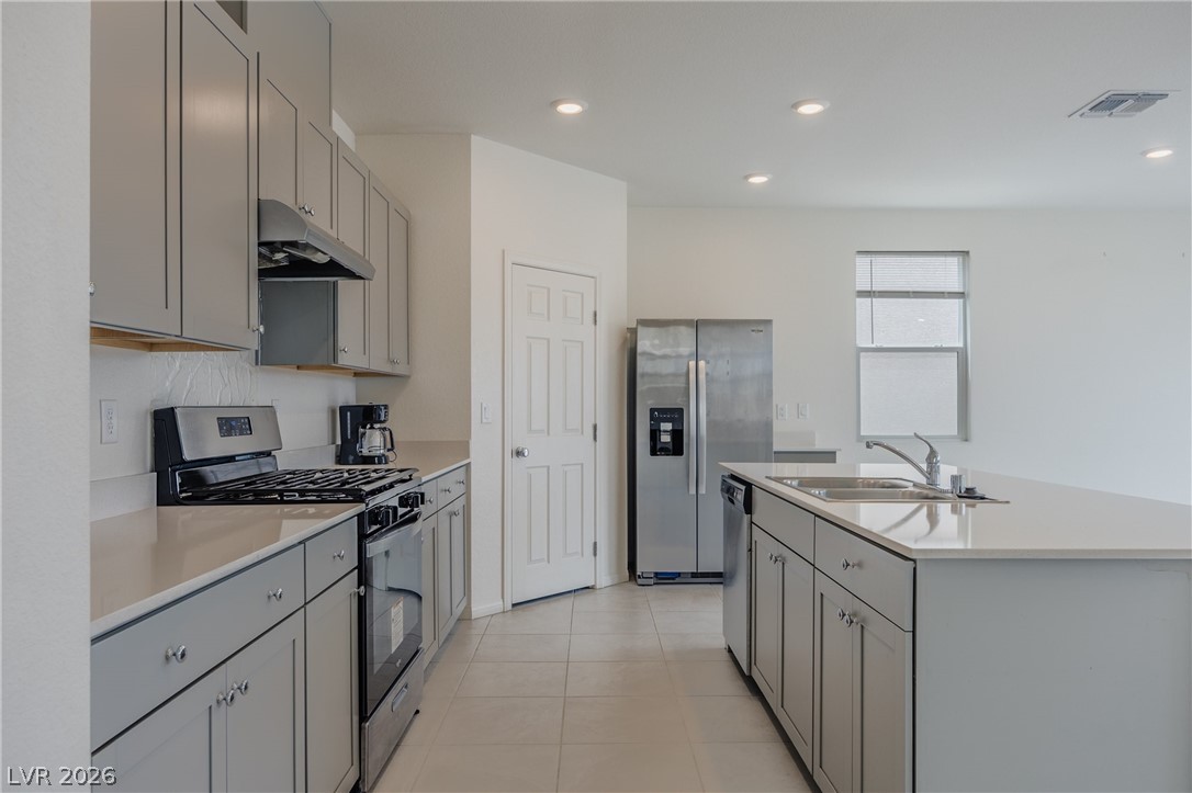 5927 Coja Street Las Vegas, NV 89113 - Photo 7 of 32 Kitchen featuring stainless steel appliances, under cabinet range hood, a sink, gray cabinets, and light countertops