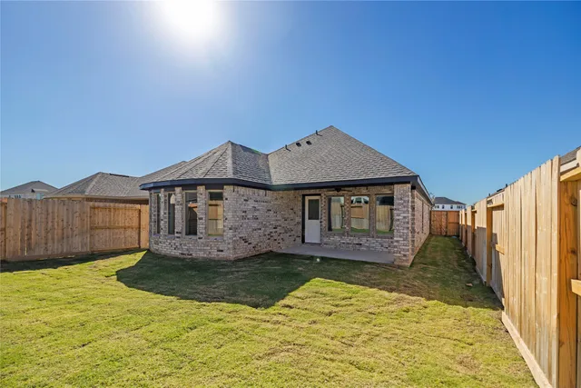 a view of a yard in front of a house with wooden fence