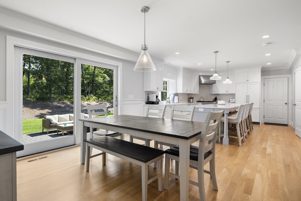 3 Bascom Hollow Harwich, MA 02645 - Photo 13 of 32 a kitchen with stainless steel appliances kitchen island granite countertop a table chairs and a wooden floor