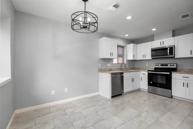 a kitchen with white cabinets sink and stainless steel appliances