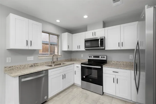 a kitchen with stainless steel appliances granite countertop a refrigerator stove and sink