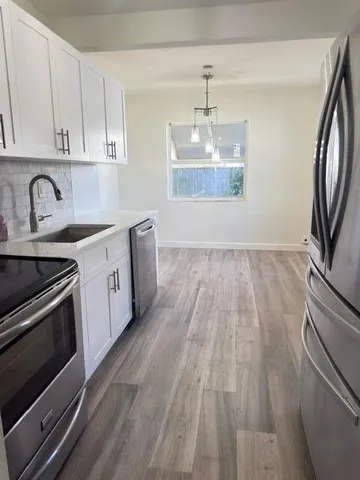 a kitchen with a sink wooden floor and stainless steel appliances