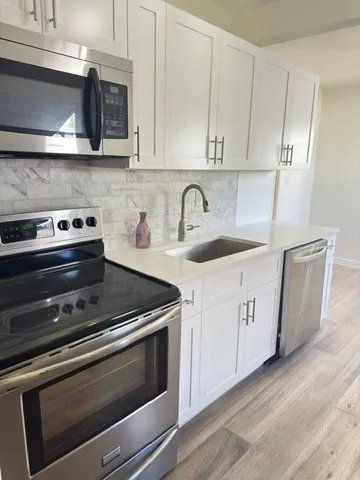 a kitchen with granite countertop white cabinets and stainless steel appliances