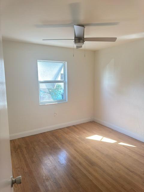1709 North J Street Lake Worth Beach, FL 33460 - Photo 7 of 10 an empty room with wooden floor chandelier fan and windows