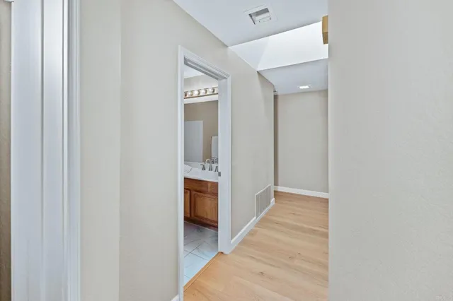 a view of a hallway with bathroom and sink