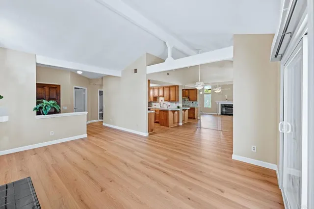 an empty room with wooden floor and a kitchen