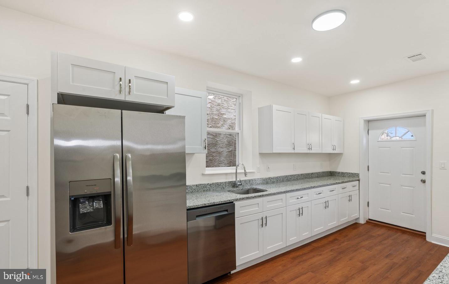 4847 Fairmount Avenue Philadelphia, PA 19139 - Photo 10 of 35 a kitchen with stainless steel appliances granite countertop a refrigerator a sink and white cabinets with wooden floor
