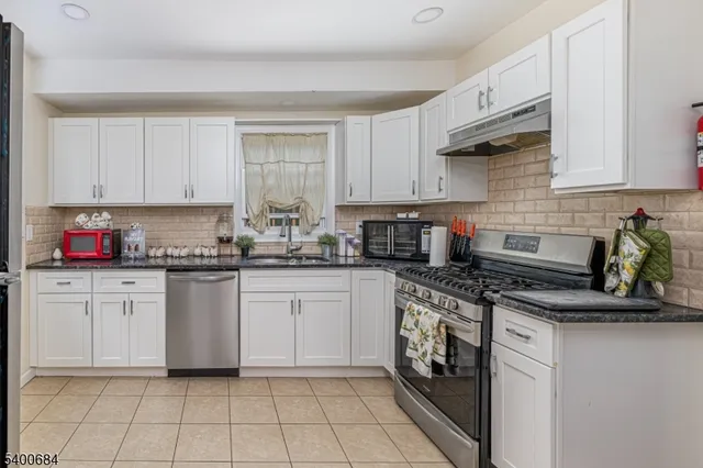 a kitchen with granite countertop white cabinets stainless steel appliances and a sink