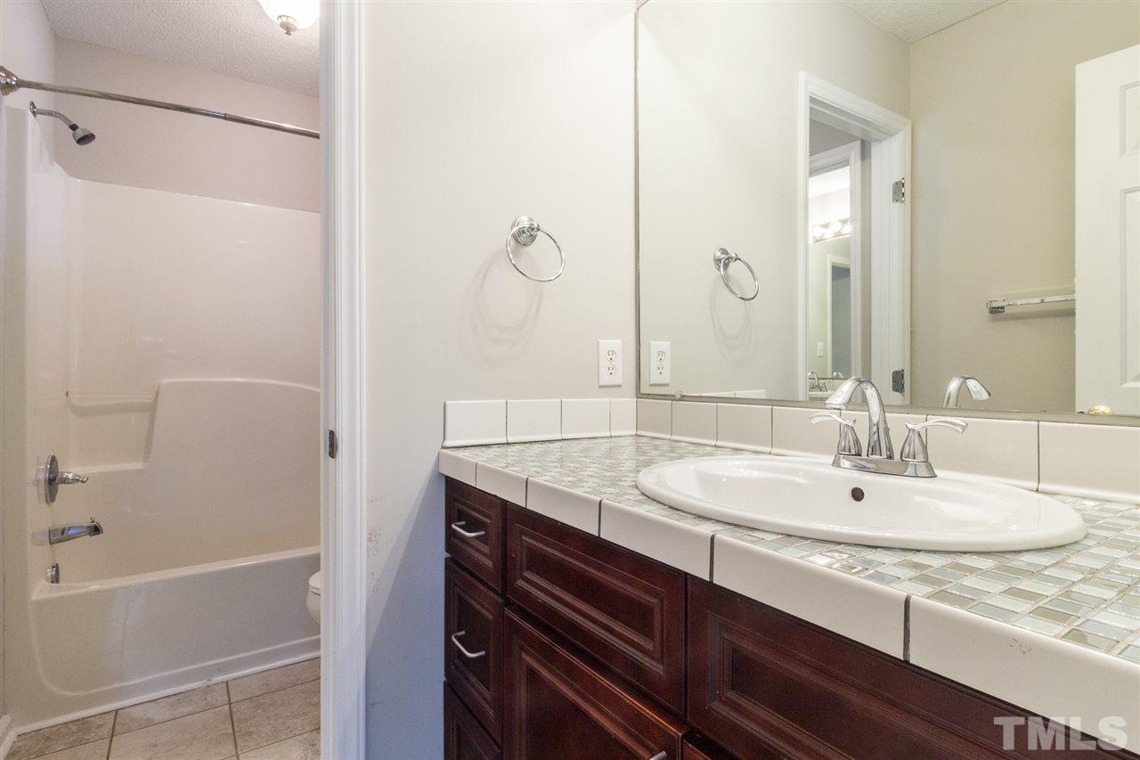 4451 Antique Lane Raleigh, NC 27616 - Photo 15 of 24 a bathroom with a granite countertop sink a mirror and a bathtub